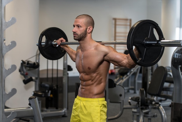 Jonge man die Barbell Squats uitvoert Een van de beste bodybuilding-oefeningen voor benen