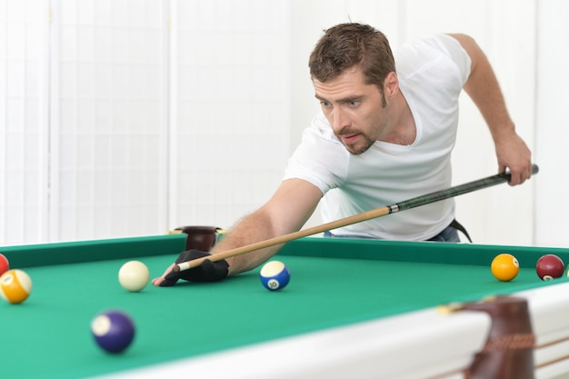 Jonge man die biljart speelt in biljartclub