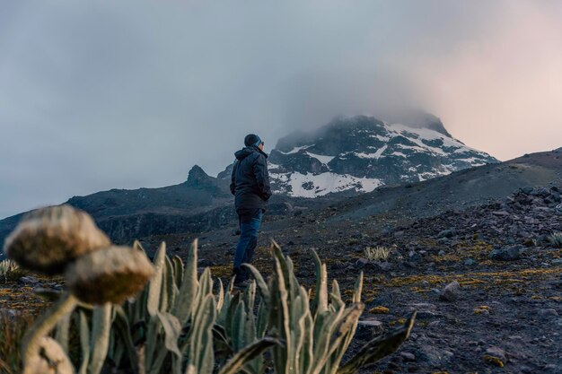 Jonge man die bovenop steen staat en geniet van een geweldige vulkanische berg