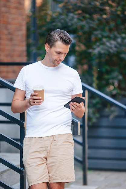 Jonge man die buiten koffie drinkt in de stad