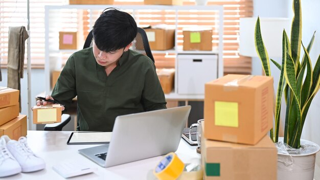 Jonge man die de bestelling van de klant controleert en de pakketdoos van het product klaarmaakt voor levering