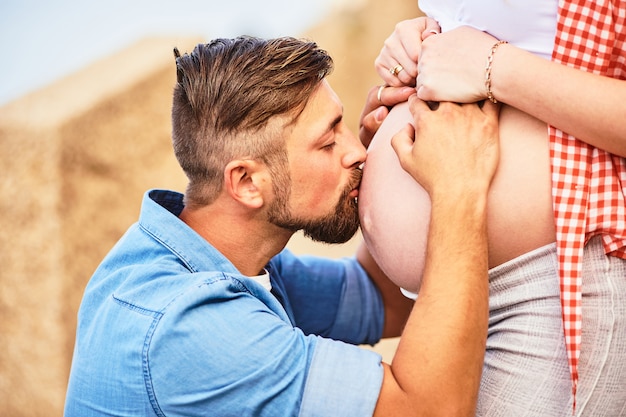 Foto jonge man die de buik van zijn zwangere vrouw kust