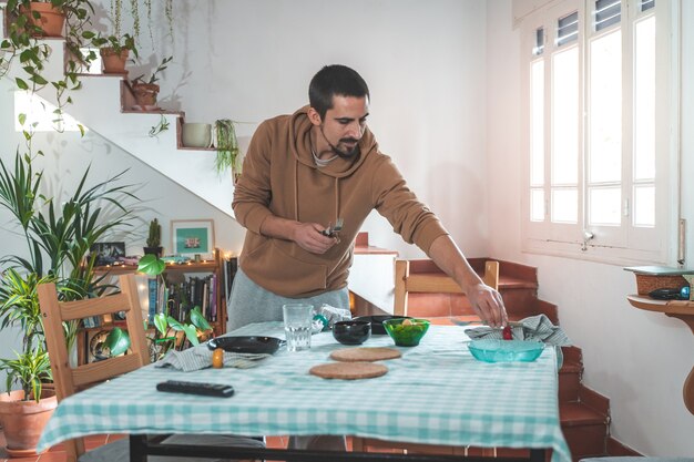 Jonge man die de tafel bedient voor de gasten tijdens een diner thuis met vrienden