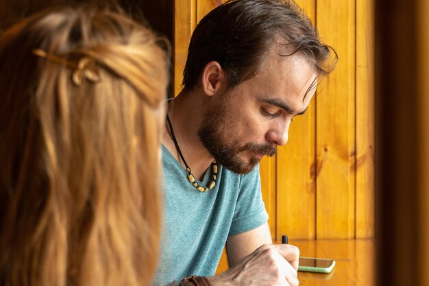 Foto jonge man die dinert in een klein café terwijl hij aan de tafel bij het raam zit