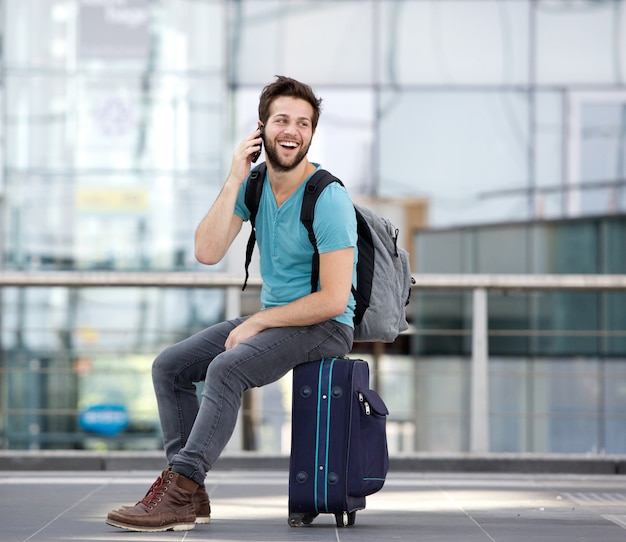 Jonge man die door mobiele telefoon op de luchthaven