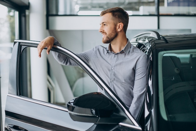 Jonge man die een auto kiest in een autosalon