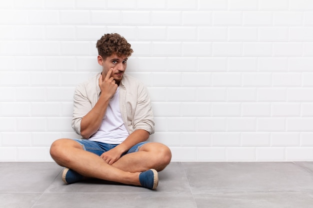 Jonge man die een oogje in het zeil houdt, niet vertrouwt, kijkt en geïsoleerd blijft