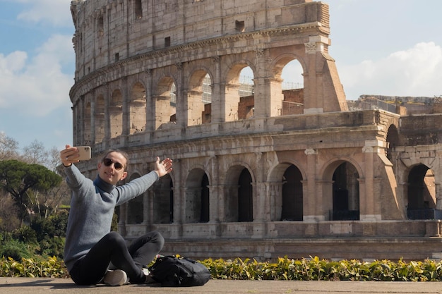 Jonge man die een videogesprek voert tijdens een bezoek aan het Colosseum in Rome