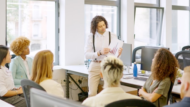 Jonge man die grafieken gebruikt tijdens een gesprek in een coworking bijeenkomst