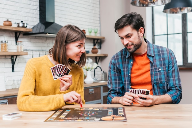 Jonge man die haar vrouw bekijkt die het raadsspel op houten bureau speelt