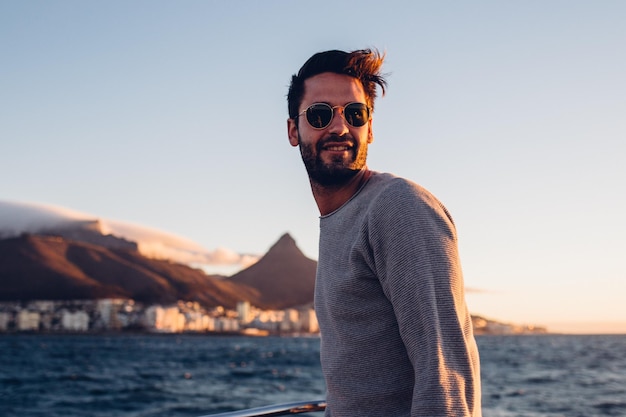 Jonge man die in een boot op zee tegen de lucht staat