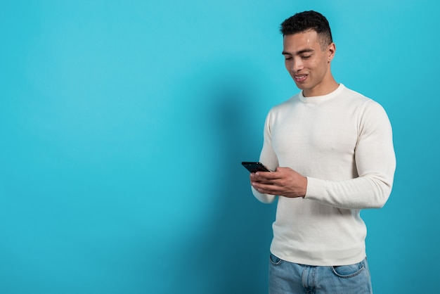 Jonge man die in wit overhemd mobiele telefoon in zijn handen houden en kijken naar het scherm