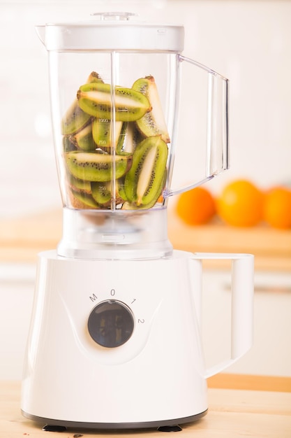 Jonge man die kiwi-smoothie in blender kookt