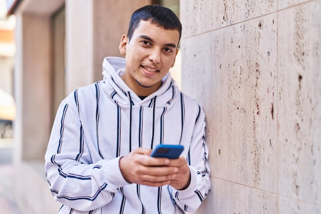 Jonge man die lacht zelfverzekerd met behulp van smartphone op straat