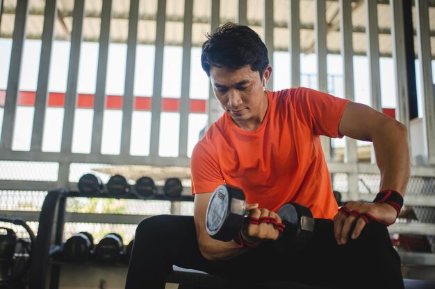 Foto jonge man die met dumbbells in de sportschool werkt