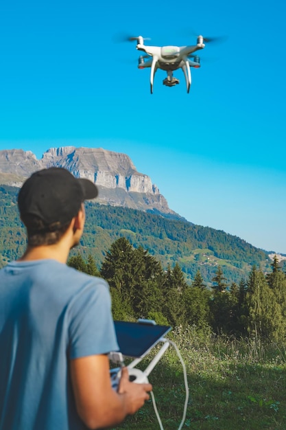 Jonge man die met een drone vliegt op een verbazingwekkende man in het berglandschap die een drone bedient met afstandsbediening