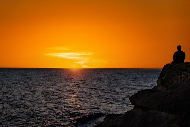 Jonge man die naar de zonsondergang kijkt op het Barbate-strand naast de Trafalgar-vuurtoren Cadiz