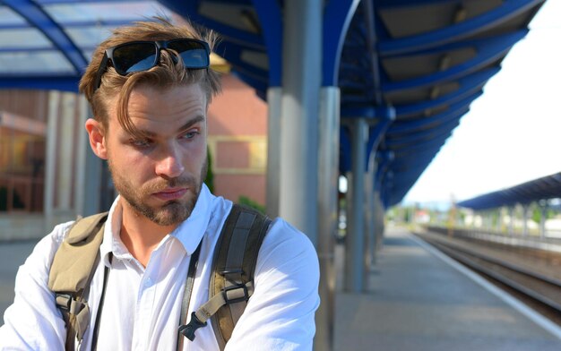 Jonge man die op het perron op het treinstation staat om te reizen