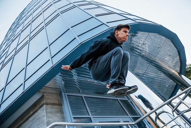 Jonge man die overdag parkour in de stad doet. Conceptie van extreme sporten.