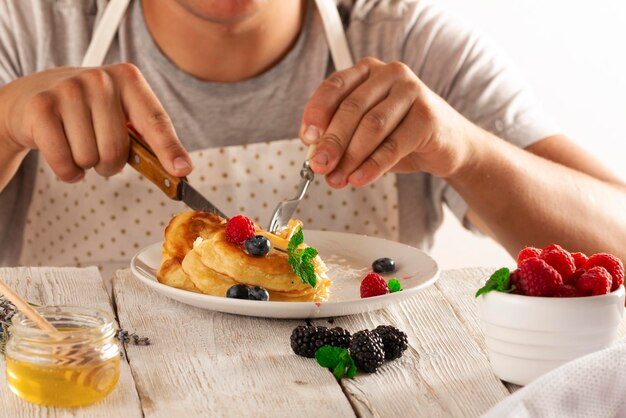 jonge man die pannenkoeken met fruit eet