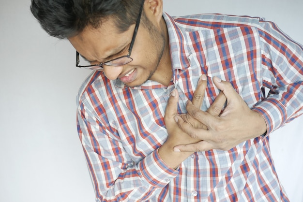 Jonge man die pijn in het hart heeft en de borst met de hand vasthoudt