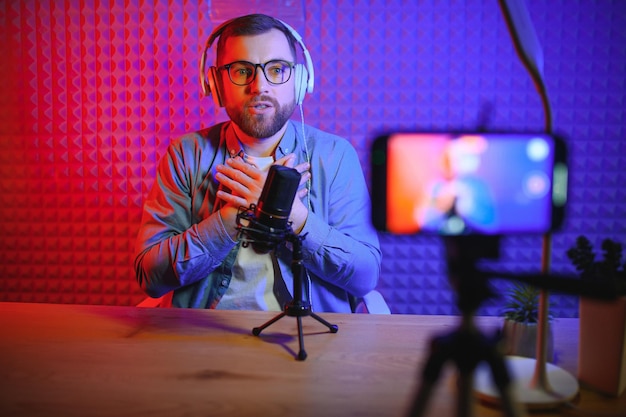 Jonge man die podcast opneemt of streamt met behulp van een microfoon in zijn kleine uitzendstudio Content creator