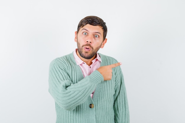 Jonge man die recht in shirt, vest wijst en zich afvraagt, vooraanzicht.