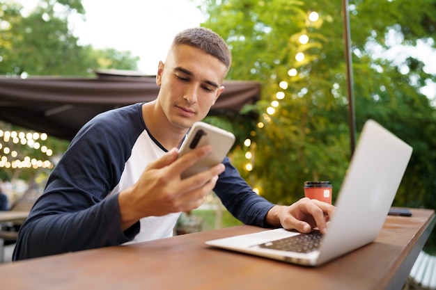 Jonge man die smartphone gebruikt terwijl hij op het terras zit