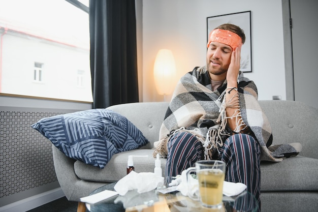 Foto jonge man die thuis verkouden is schot van een jonge man die op zijn bed zit terwijl hij zich thuis onwel voelt proberen warm te blijven zieke man