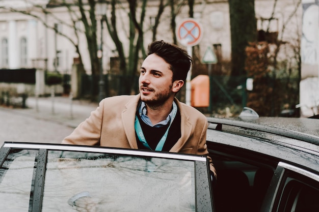 Jonge man die tijdens het regenseizoen een natte auto in de stad betreedt