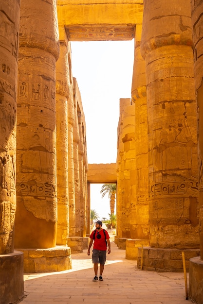 jonge man die tussen de hiëroglifische zuilen van de tempel van Karnak, Egypte slentert