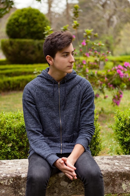 Foto jonge man die wegkijkt terwijl hij op planten zit