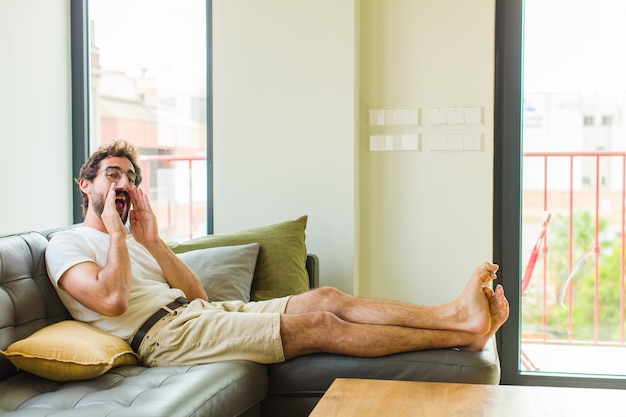 Jonge man die zich blij, opgewonden en positief voelt en een grote schreeuw geeft met de handen naast de mond