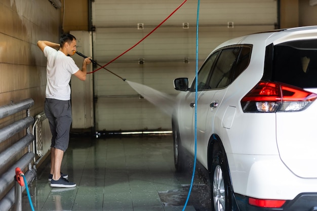 Jonge man die zijn auto schoon spuit