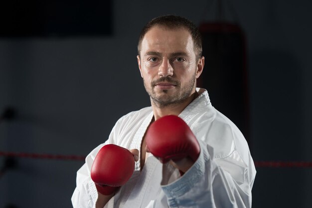 Jonge man die zijn karate oefent, beweegt witte kimono zwarte band