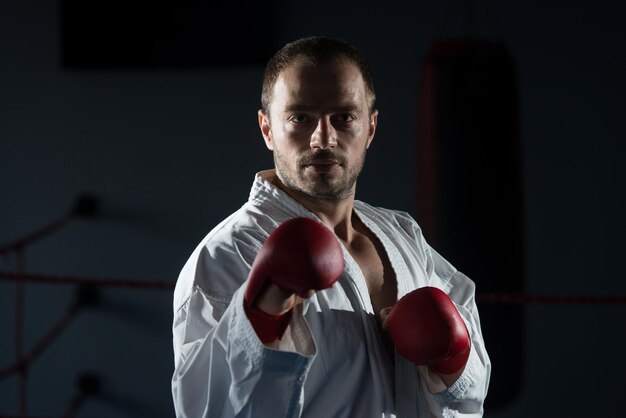 Jonge man die zijn karate oefent, beweegt witte kimono zwarte band