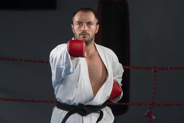 Jonge man die zijn karate oefent, beweegt witte kimono zwarte band