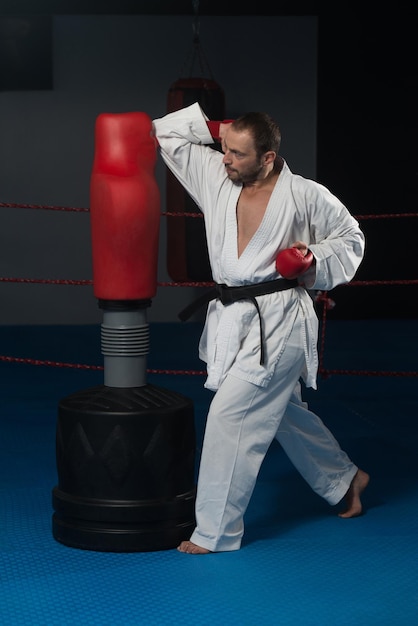 Jonge man die zijn karate oefent, beweegt witte kimono zwarte band