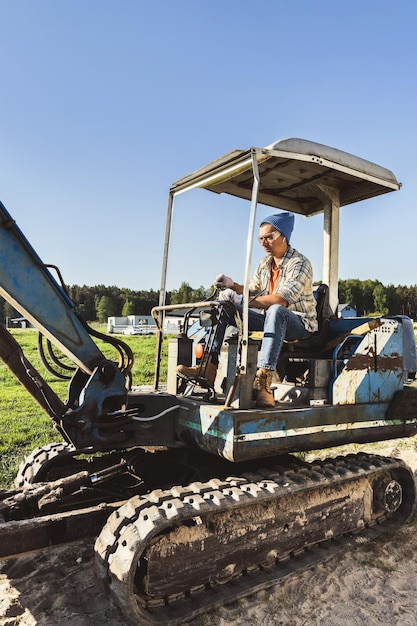 Foto jonge man die zijn oude graafmachine bedient tijdens zijn werk op een bouwplaats