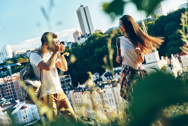 Jonge man die zijn vriendin fotografeert terwijl hij buiten op de top van de heuvel staat