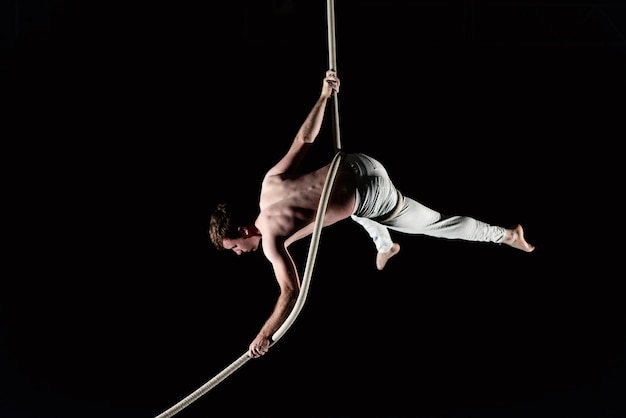 Jonge man doet gymnastiek tegen een zwarte achtergrond
