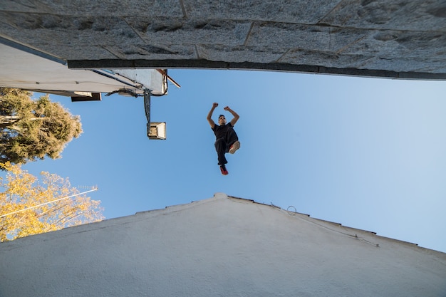 Jonge man doet indrukwekkende parkour sprong van het ene dak naar het andere