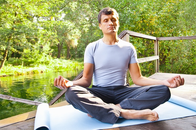 Jonge man doet yoga lotus pose in park