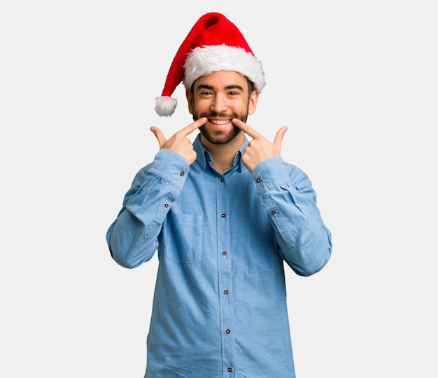 Jonge man draagt santa hat glimlach, wijzende mond