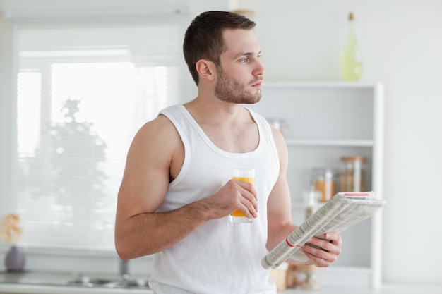 Jonge man drinken sinaasappelsap tijdens het lezen van het nieuws