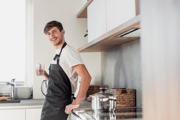 jonge man drinkt schoon water dat in de thuiskeuken staat. foto met kopieerruimte