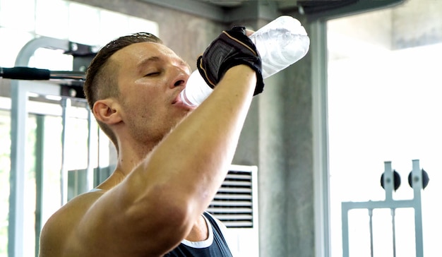 Foto jonge man drinkt water in de sportschool.
