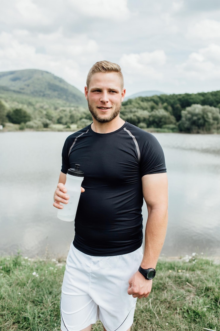 Foto jonge man drinkt water tegen het meer.