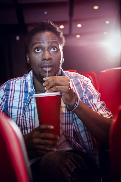 Jonge man een film kijken en frisdrank drinken