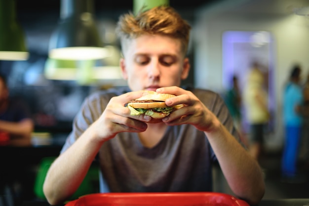 Jonge man een heerlijke hamburger eten